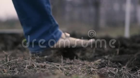 一个穿着蓝色牛仔裤男人的腿在地上挖铲子视频的预览图