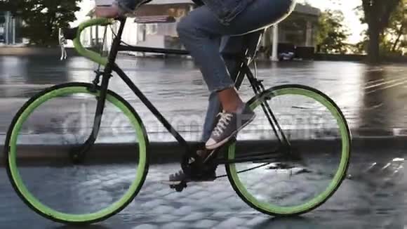 特写镜头女性脚骑自行车在早上由铺好的城市街道与湿沥青铺侧视图视频的预览图