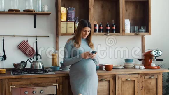 厨房里带智能手机的孕妇视频的预览图