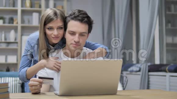年轻夫妇通过信用卡在笔记本电脑上成功网上购物视频的预览图