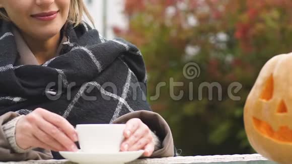 万圣节前夜迷人的女士在雕刻的千斤顶灯旁喝咖啡视频的预览图