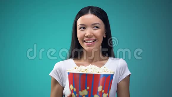 漂亮的年轻女子带着一大杯爆米花快速地瞥了一眼在电影院里调情视频的预览图
