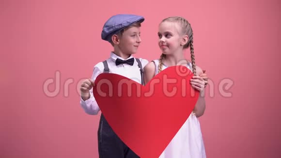 年轻的男孩和女孩躲在红纸心和亲吻情人节视频的预览图