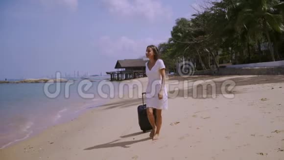 商务女性带着一个手提箱走在美丽的大海的岸边自由职业概念期待已久的休闲概念视频的预览图