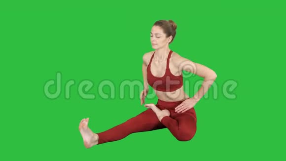 年轻有魅力的女性练习瑜伽坐在头对膝前弯曲练习janusirsasana在绿色上摆姿势视频的预览图