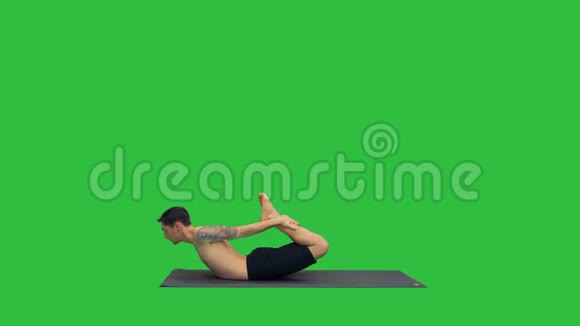 运动肌肉的年轻瑜伽男子做后弯运动达努拉萨纳弓姿势在绿色屏幕铬键视频的预览图