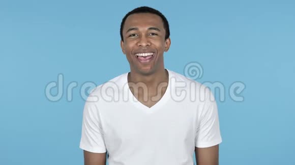 可笑的笑年轻的非洲男人蓝色的背景视频的预览图