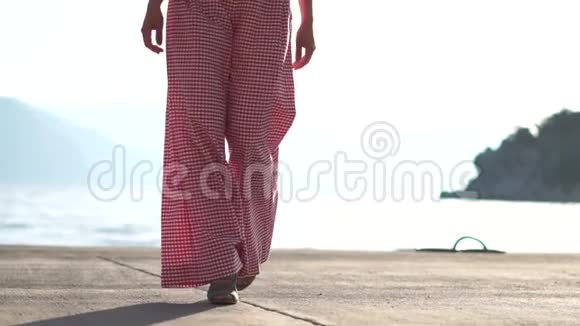 一个穿高跟鞋的女人慢吞吞地走在海滨视频的预览图