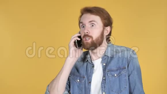 兴奋的红发男子打电话黄色背景视频的预览图