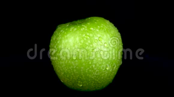 水喷在绿苹果上在黑色的背景下视频的预览图