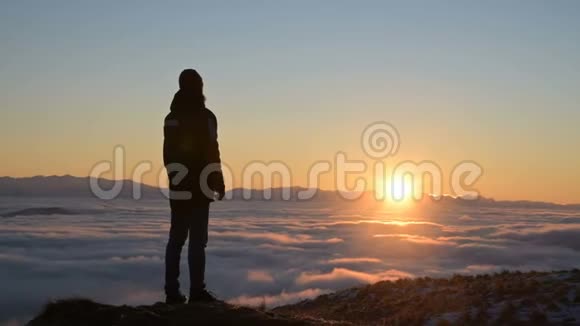 一个人的剪影站在云层上方的处凝视着夕阳宁静的概念视频的预览图