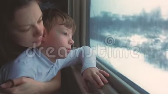妈妈和儿子正在冬天的风景中看着火车的窗户视频的预览图