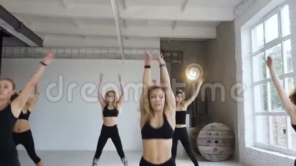在健身班a组6名身穿黑色运动服的年轻女性进行跳跃练习举手健康视频的预览图