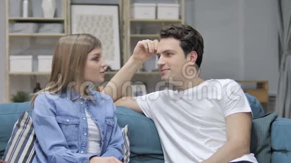 快乐的女孩和男朋友在沙发上放松讨论视频的预览图