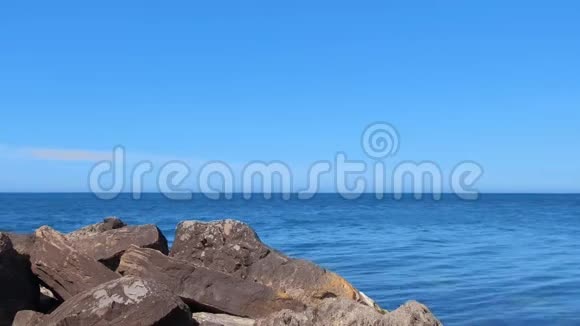 在阳光明媚的日子里海洋海岸有着巨大的鹅卵石的海景视频的预览图