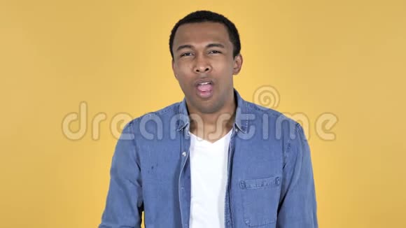 年轻的非洲男子在黄色背景下打哈欠和伸展身体视频的预览图
