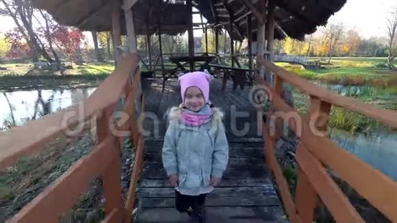 秋天快乐的女孩走在木桥上背景河流视频的预览图