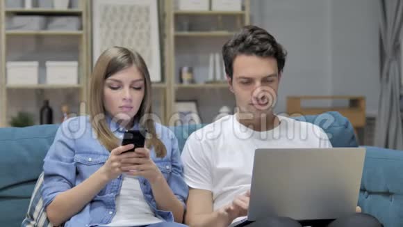 年轻夫妇在家使用智能手机和笔记本电脑聊天视频的预览图