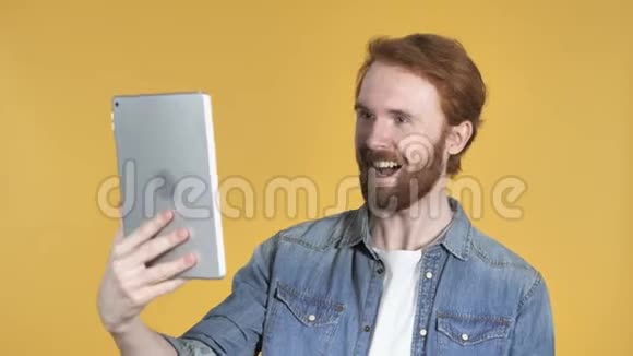 红发男子通过平板电脑进行视频聊天黄色背景视频的预览图