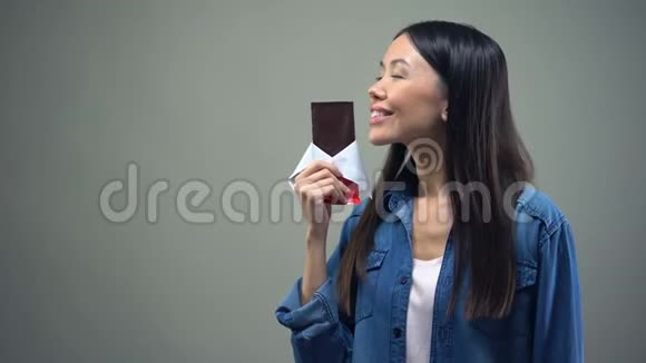 有趣的女孩享受巧克力棒的甜香亲吻它女人保持饮食视频的预览图