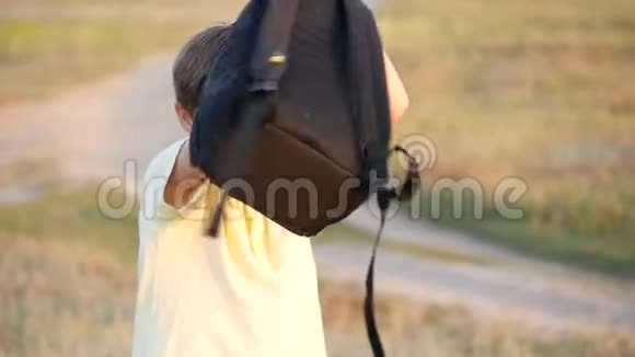 一个快乐的少年正在绕着他转一个背包这男孩在学校一天结束时感到高兴视频的预览图