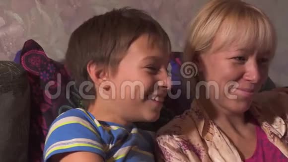 年轻女子妈妈和她的儿子一起在笔记本电脑上看有趣的电影视频的预览图