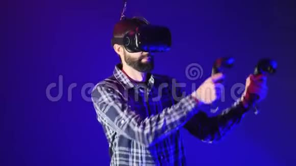 戴着互动虚拟现实头盔的留胡子男子手里拿着遥控器跳舞享受虚拟现实视频的预览图