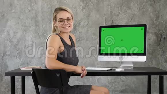 漂亮的女商人看着电脑屏幕附近的照相机绿屏模拟显示视频的预览图