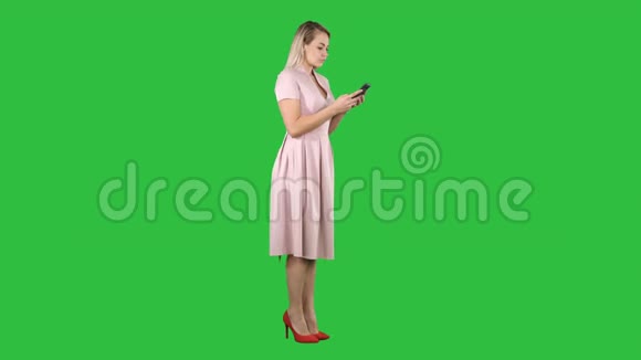 金发少女女人穿着粉红色短信在她的智能手机上的绿色屏幕Chroma键视频的预览图