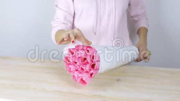 女人手纠正花的包装粉红色郁金香花束视频的预览图