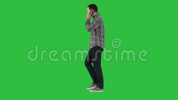 年轻的胡须男在绿色屏幕上的手机上行走和交谈Chroma键视频的预览图