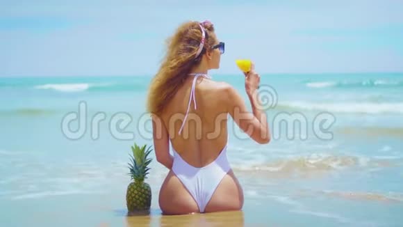 开朗美丽的少女正背对着海边的沙滩坐着视频的预览图
