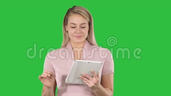 中镜头的美女使用平板电脑翻页并在相机上看绿色屏幕Chroma键视频的预览图