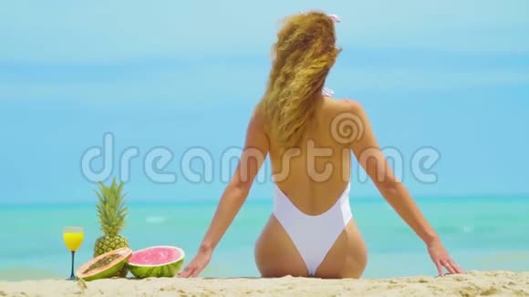 开朗美丽的少女正背对着海边的沙滩坐着视频的预览图