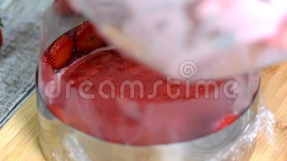 厨房里的女人做草莓慕斯蛋糕在糖果圈里浇草莓慕斯甜食视频的预览图
