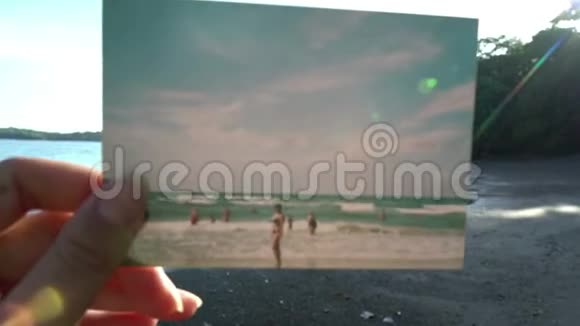 特写手握宝丽来照片前美丽的热带海滩日落旅游理念放大眩晕视频的预览图