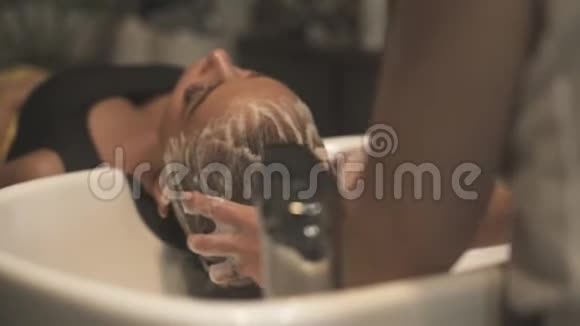长发妇女接受洗头和头部按摩同时在美发沙龙水疗嗜血学家洗头视频的预览图