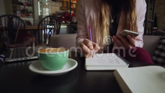 女人坐在咖啡店的木桌上喝咖啡使用智能手机女人在咖啡厅用电话学生视频的预览图