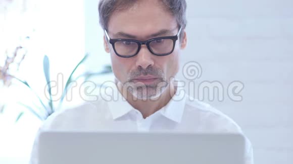 把好奇的中年男人关在笔记本电脑上视频的预览图