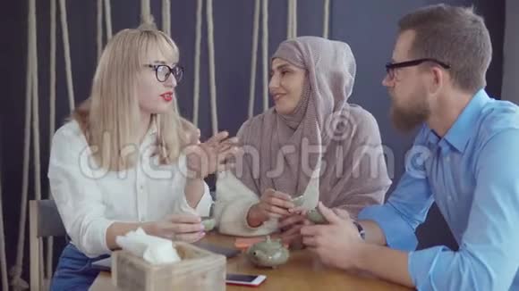 三个白人和穆斯林朋友男人和女人聊天喝茶视频的预览图