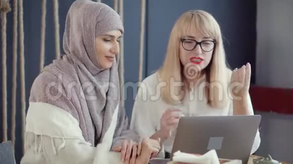 两个女朋友在咖啡馆聊天在笔记本电脑上观看视频的预览图