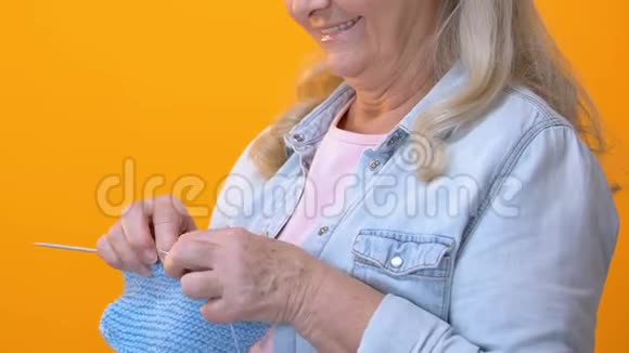 女性养老金领取者编织蓝色围巾在相机中微笑手工制作视频的预览图