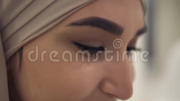 特写一位年轻而神秘的阿拉伯女人的肖像她身穿米色头巾头戴头巾微笑着看着镜头视频的预览图