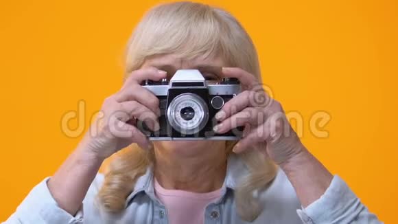 微笑的老太太用老式相机拍照退休爱好工作视频的预览图
