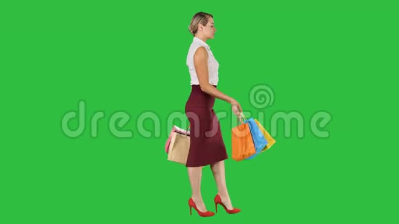 购物愉快女人拿着五颜六色的购物袋走在绿色的屏幕上Chroma键视频的预览图