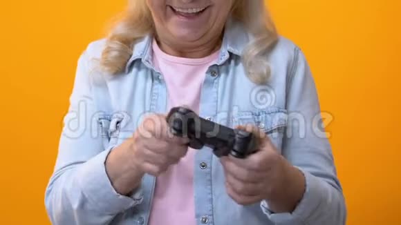 兴奋的奶奶在明亮的背景下通过操纵杆玩电子游戏休闲乐趣视频的预览图