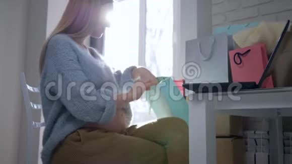 照顾未来的孩子快乐的大肚子产妇为未来的宝宝坐着上网检查衣服视频的预览图