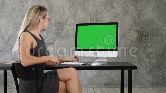 开朗的年轻女人坐在办公室里和相机交谈在电脑上展示一些东西绿屏模拟视频的预览图