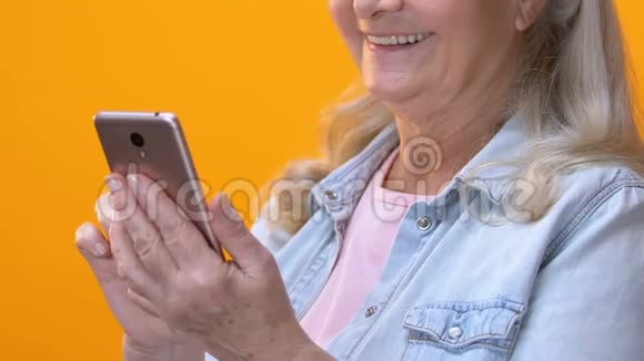 智能手机上的老年女性打字信息滚动移动应用程序电话资费视频的预览图