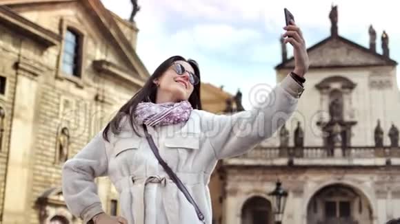 历史城堡背景下快乐的旅游女性微笑着使用智能手机自拍视频的预览图